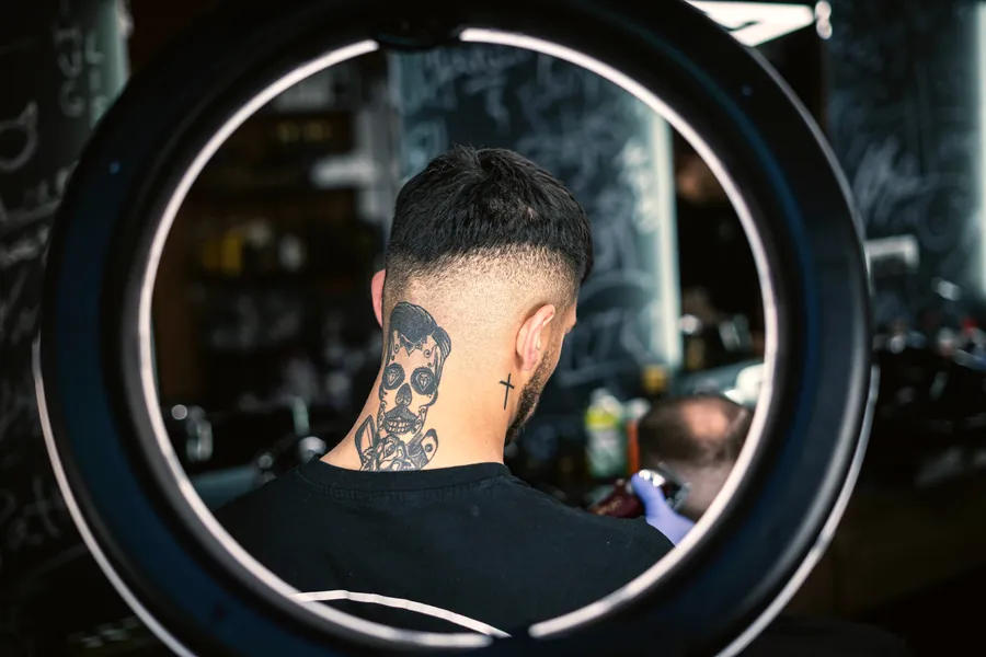 A tape-up viewed through a ring light, showing the neckline and back of a fresh skin fade.