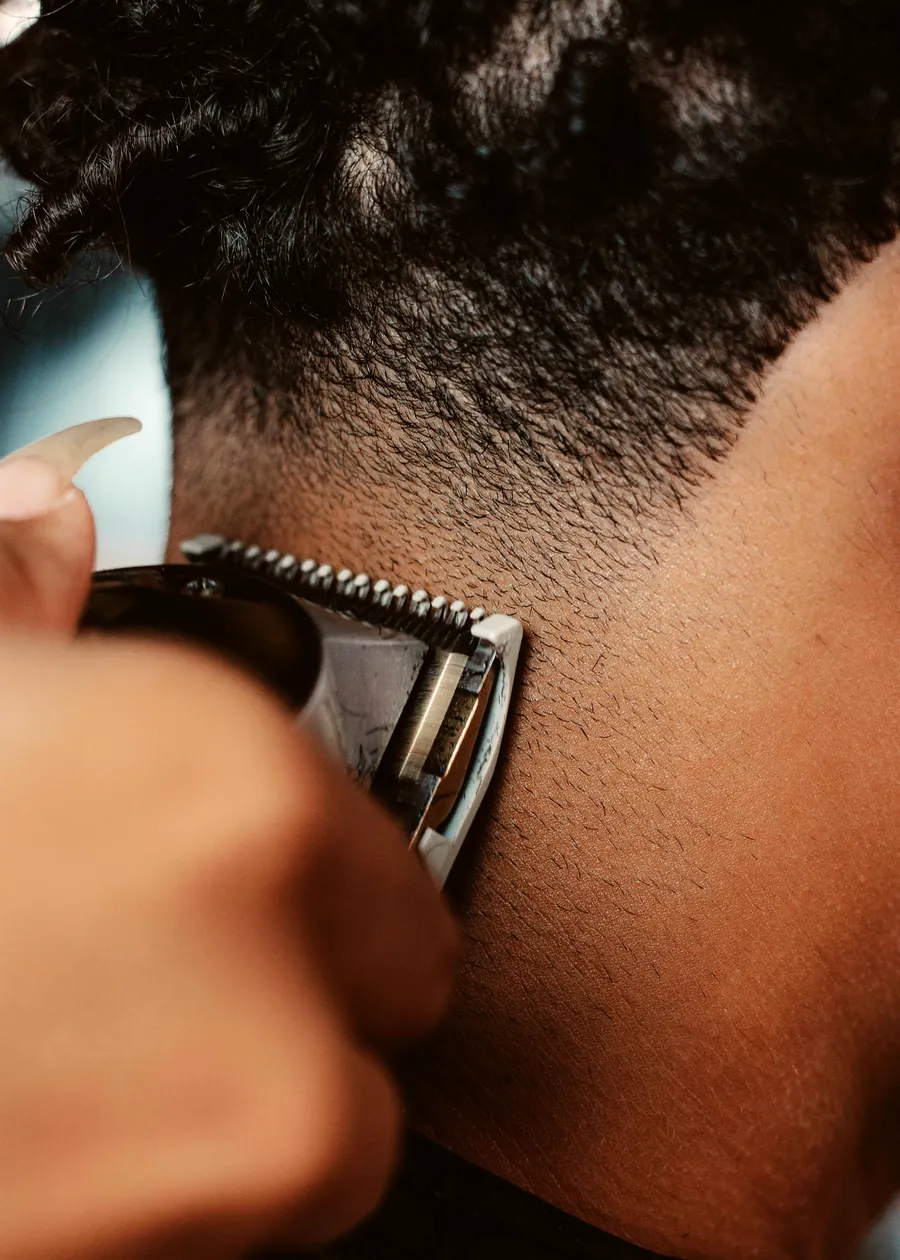 Close detail of clippers blending the guard line on the back of a fade.